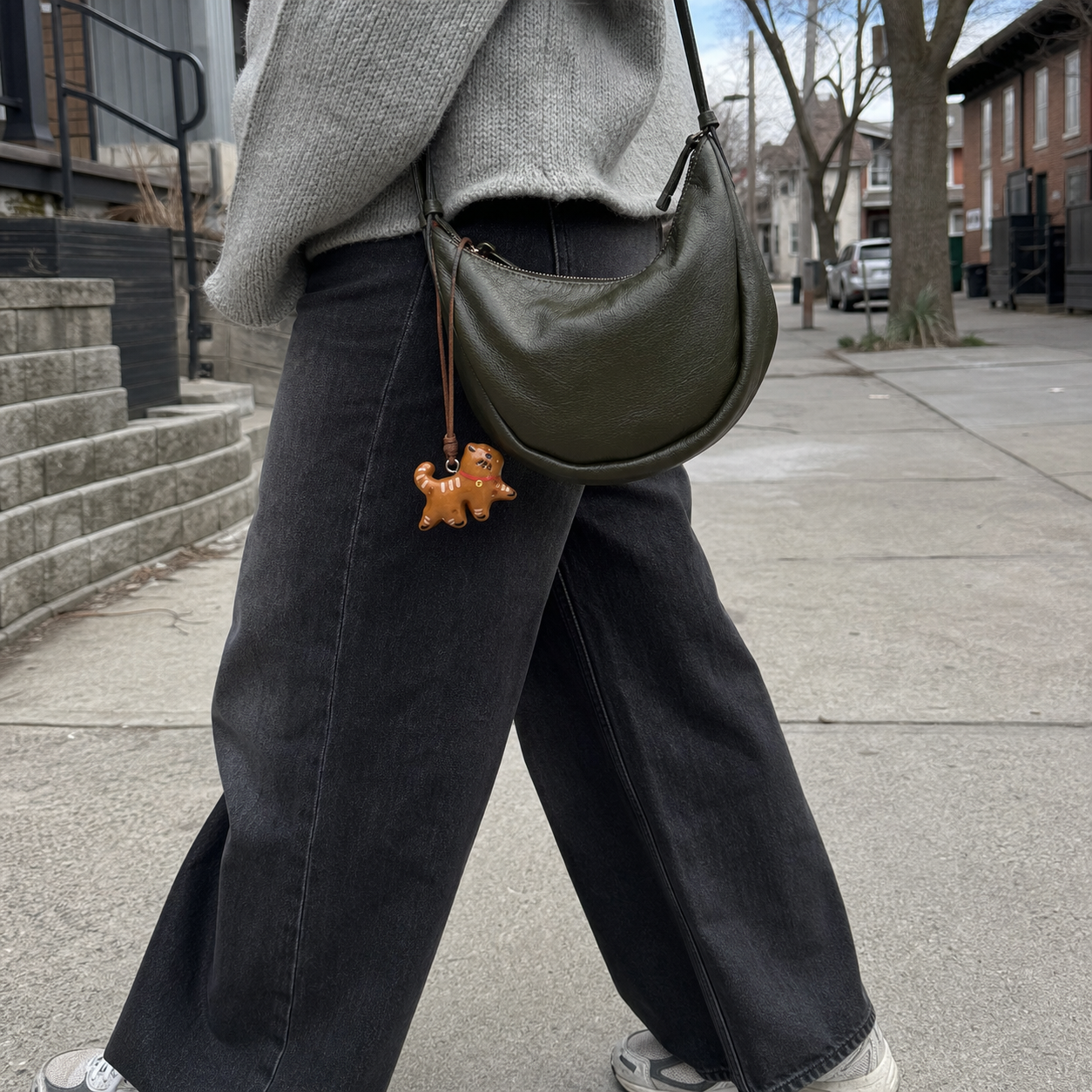 Walking cat bread bag charm on an olive shoulder bag in a Toronto street setting