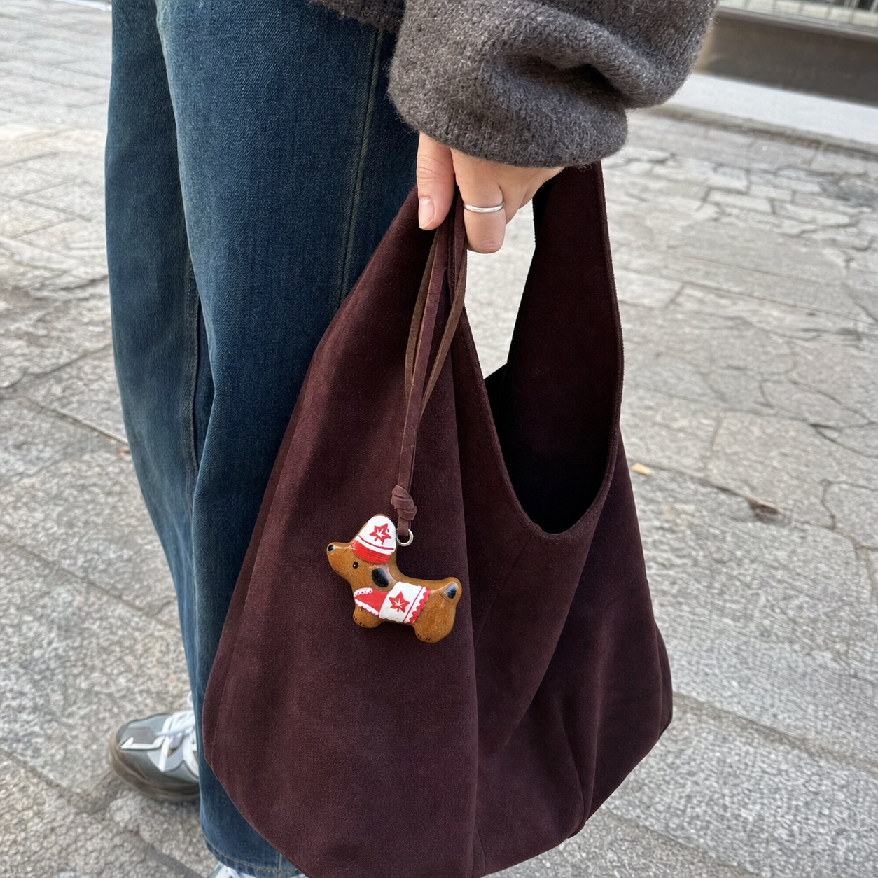 Red and white hand-painted dachshund bread charm on a burgundy bag outdoors