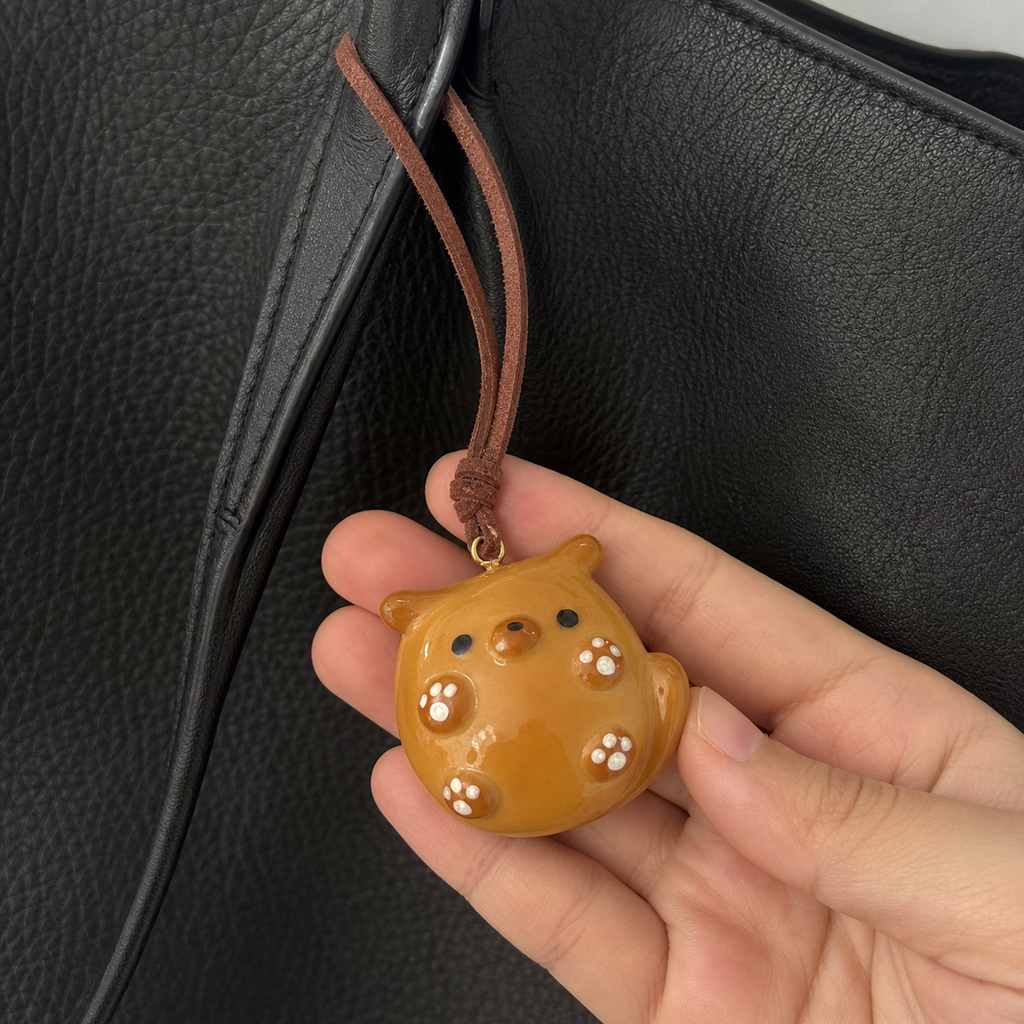 Close-up of Piglet Paws bread bag charm and brown leather cord