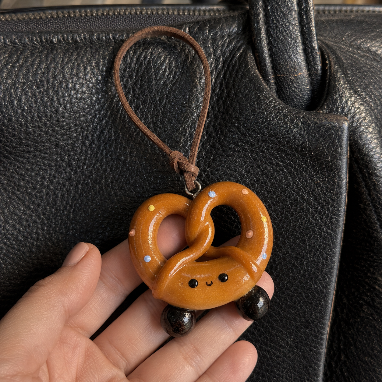 Close-up of confetti sweet pretzel bread bag charm with brown leather hanging cord