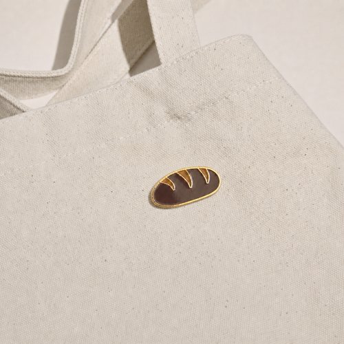 Baguette Bread Pin displayed on a natural canvas tote bag