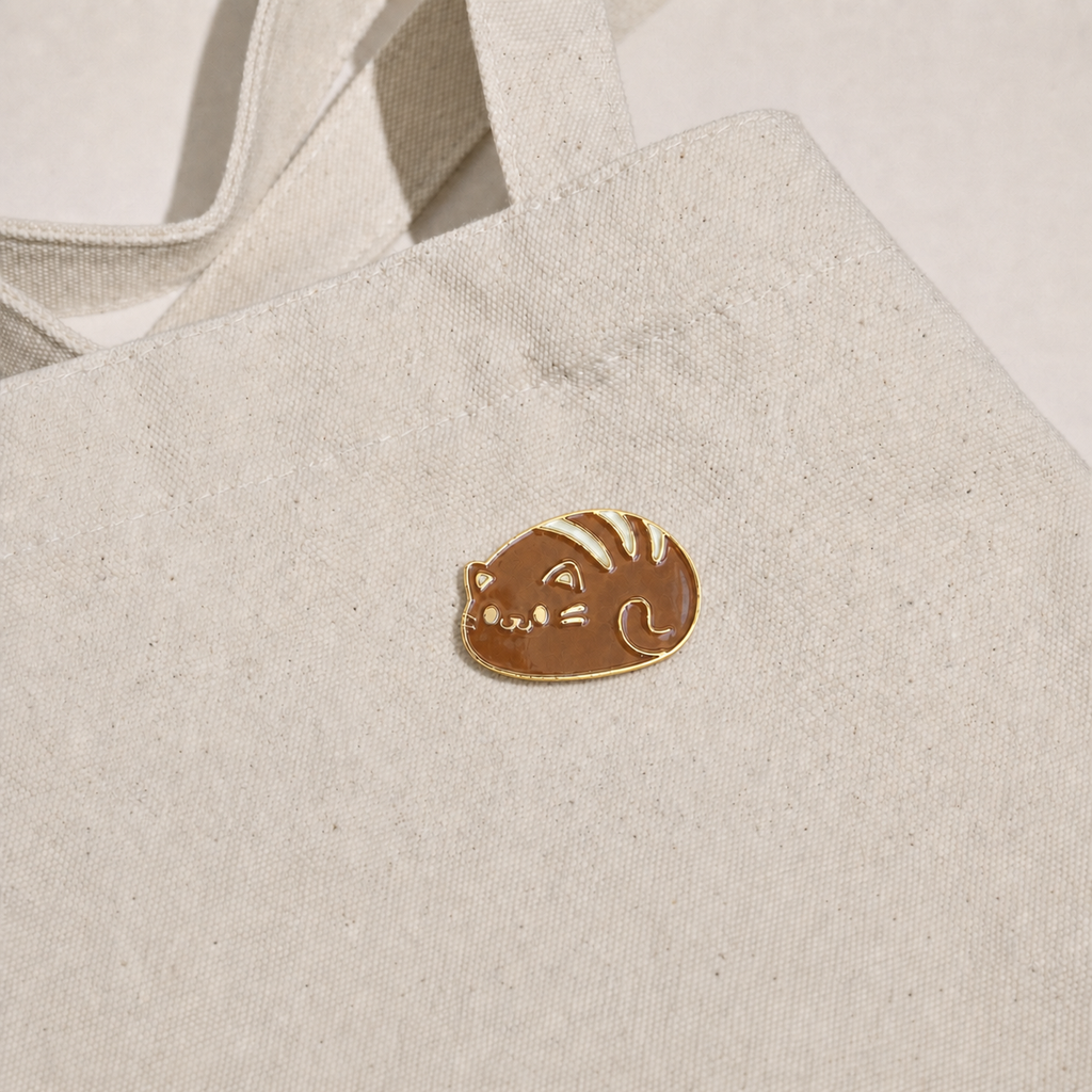 Cat Bread Pin displayed on a natural canvas tote bag