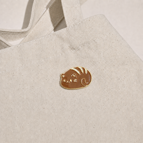 Cat Bread Pin displayed on a natural canvas tote bag