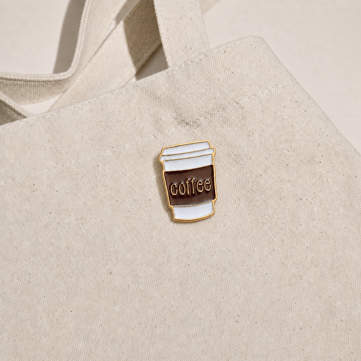 Coffee Cup Pin displayed on a natural canvas tote bag