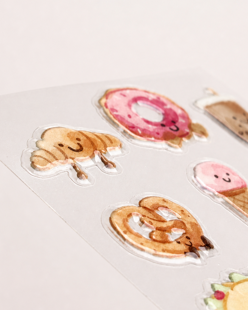 Angled close-up of croissant, donut and pretzel raised 3D stickers