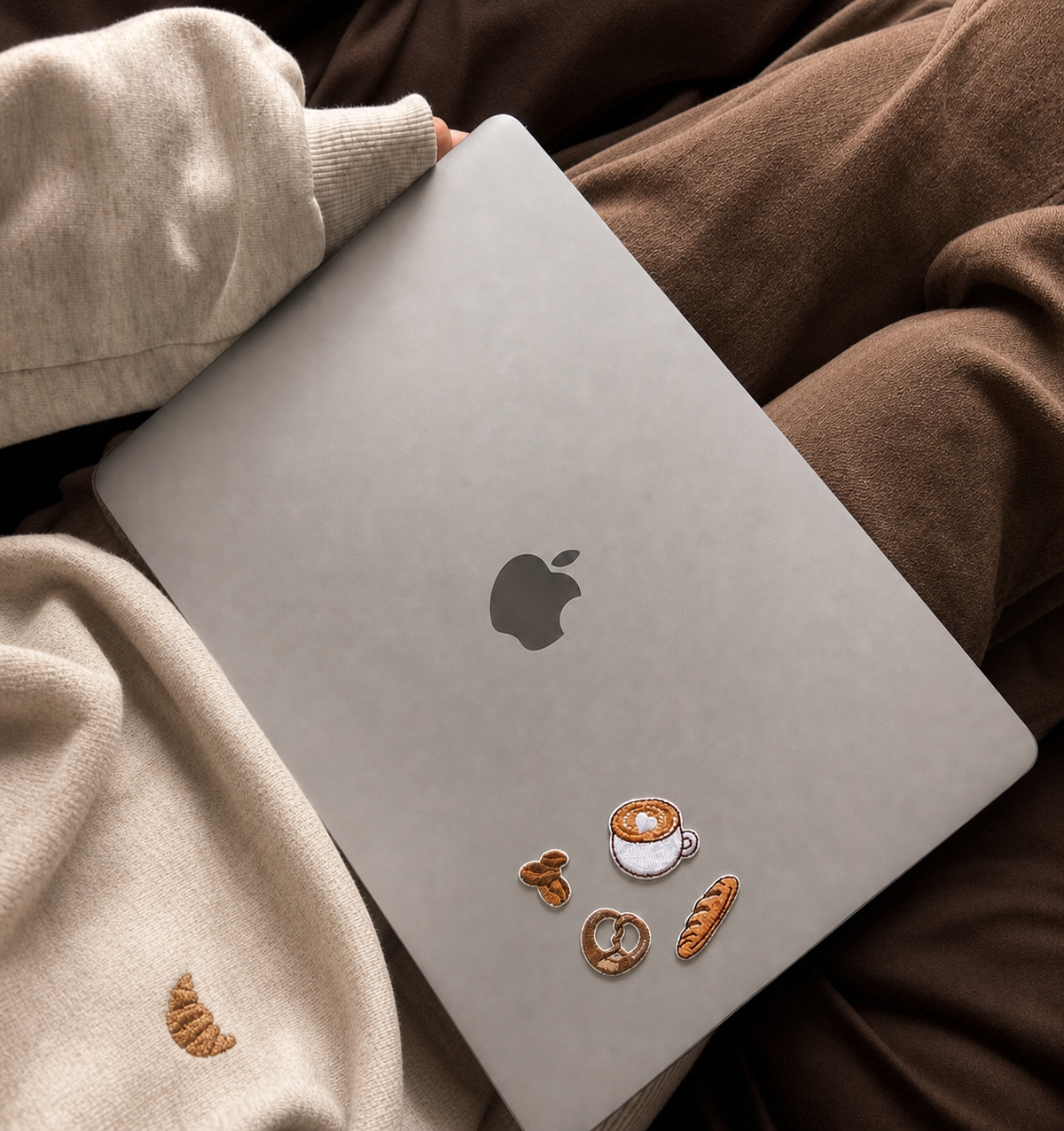 Tiny peel-and-stick embroidered coffee and bakery patches on a silver MacBook