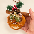 Hand holding Classic Cinnamon Pretzel Christmas ornament showing its scale
